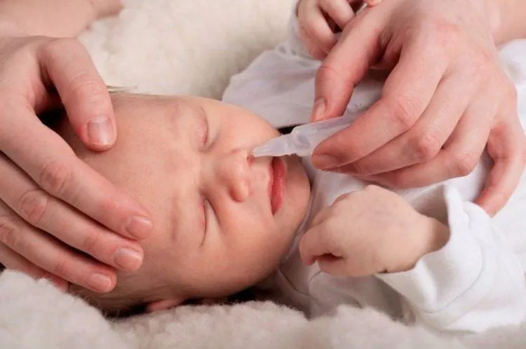 Hình ảnh minh họa cảnh nhỏ mũi cho trẻ sơ sinh, nhấn mạnh sự cần thiết của việc thực hiện đúng cách để tránh nguy hiểm.