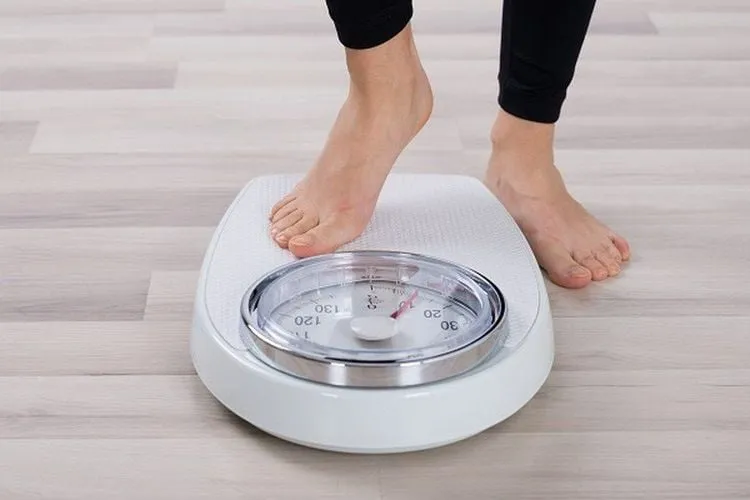 Người đàn ông đang đo cân nặng, minh họa mối liên hệ giữa cân nặng và sức khỏe nam giới.