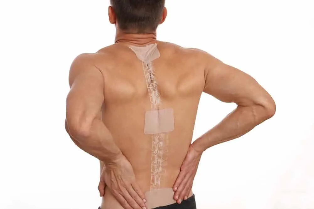 Một người phụ nữ trẻ tuổi đang dán miếng dán lên lưng dưới để giảm đau mỏi